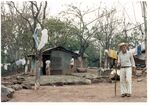 Unidentified man standing in front of a house in a rural village in El Salvador, 1986 by unknown