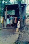 A group of women stand outside a house in a village in El Salvador by unknown