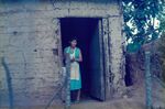 A woman stands in a doorway in a rural village in El Salvador by unknown