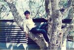 View of a teenage boy sitting in a tree in a rural village in El Salvador by unknown